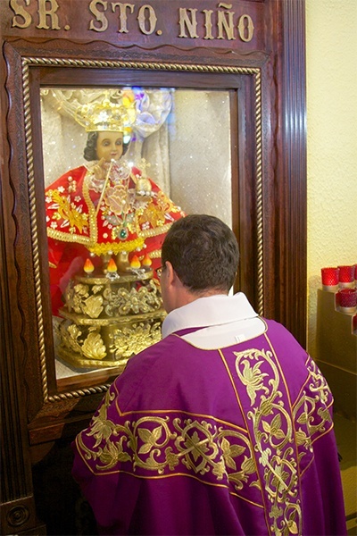 Father Carlos Vega pastor at St. Bernard Church in Sunrise, kneels and prays in front of the image of "El Santo Niño de Cebú." The image was brought from Cebú, Philippines and now resides permanently in its own shrine at St. Bernard.