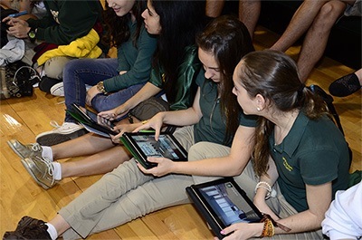 Immaculata-La Salle students check their iPads during the Apple Distinguished Program award presentation. At the same time, everyone received an email with a rendering of the soon-to-be-remodeled library, which will feature glass walls that can be written on and more of a lounge feel.