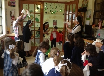 Newly-elected Pope Santiago stands in the doorway to bless his teachers and fellow classmates as they wave white tissues signifying white smoke.