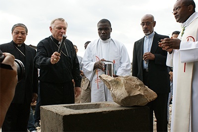 Archbishop Wenski blesses the cornerstone that was embedded in one of the columns of the planned multipurpose building as Archbishop Bernardito Auza, left, papal nuncio to Haiti, watches. At right are Bishop Joseph Lafontant, auxiliary bishop of Port-au-Prince and Bishop Launay Saturné, bishop of Jacmel.