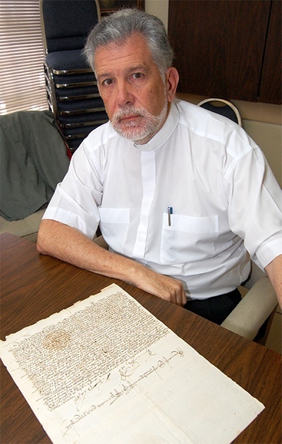 Father Jose Luis Menendez with one of the 10,000 original documents in the historical archive, which also has 400,000 digital copies of documents.