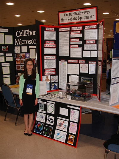 Blessed Trinity seventh grader Daniela Rodriguez poses with her award winning science project, a robot named Steve which captures brain activity and nerve impulses to produce movement.