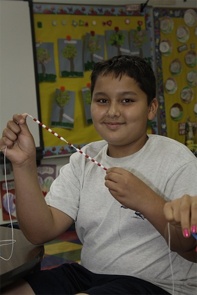 Our Lady of the Lakes sixth-grader Jonathan Colon holds up his partially made rosary.