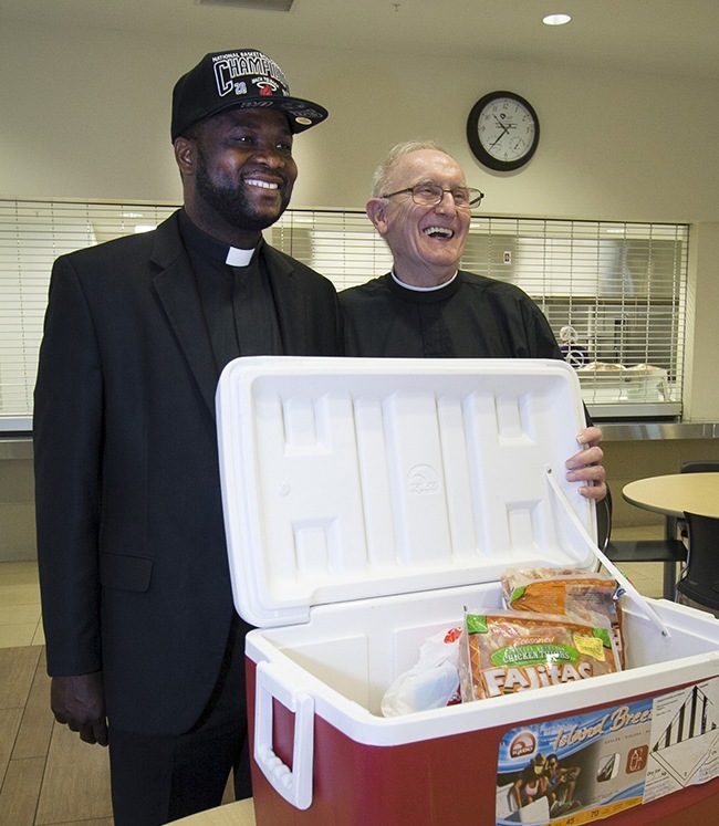 Msgr. Chanel Jeanty, archdiocesan vicar general, and Brother Bill Osmanski, religious superior of the Brothers of the Good Shepherd who work at Camillus House, pose for the camera with the San Antonio meat.