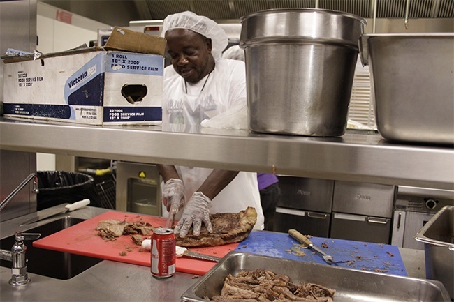 Camillus House worker Lorenzo Hudson cuts up a brisket for lunch - but not the brisket from San Antonio, which had to be thawed and would be served a day later.