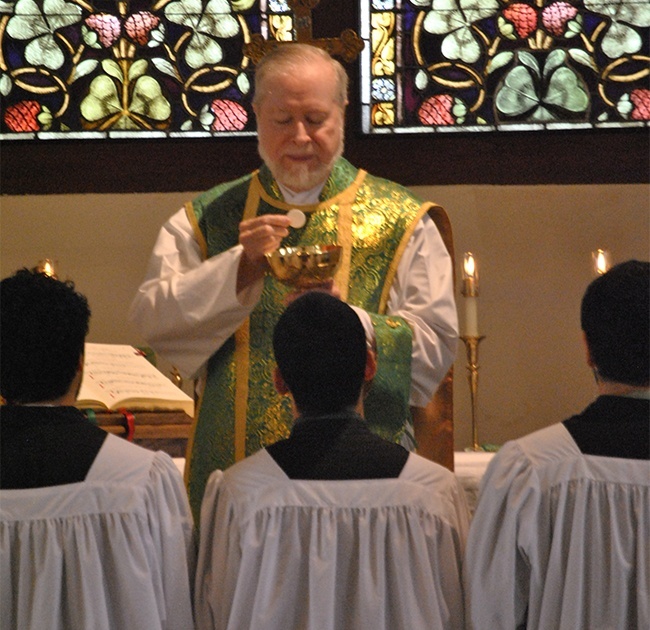 Father Joseph Fishwick distributes Communion to altar servers. As an act of reverence, Communion is received kneeling, on the tongue.