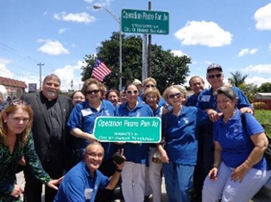 The now-grown children of Pedro Pan gather at the corner of West 12th Avenue in Hialeah for the street renaming and dedication ceremony. At left is Father Jose Espino, pastor of San Lazaro Parish in Hialeah, and a Pedro Pan himself.