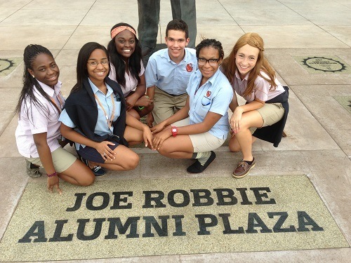 Students gather at the Joe Robbie sign at SunLife Stadium. Tim Robbie, Joe Robbie�s son, graduated from Archbishop Curley Notre Dame. In 1991, he was the youngest chief executive in the National Football League and credited for turning the Miami Dolphins franchise around. Pictured, from left: Aisha Louis, Tiffany Ospin, Milienne Bonenfant, Daniel Briz, Annasthasia Poitier, Rhian Romanik.