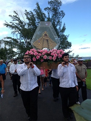 Miembros de la Pastoral Juvenil Hispana llevan hacia la Ermita la imagen peregrina de la Virgen de la Caridad despues de la procesión marítima.