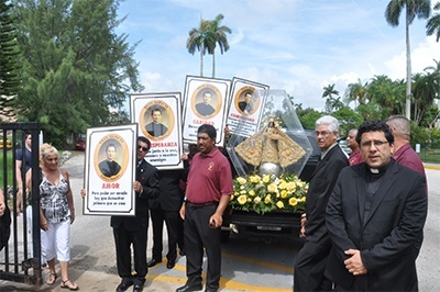 Father Juan Carlos Paguaga, right, pastor of St. John Bosco Church in Little Havana, is accompanied by members of his community as he returns the pilgrim statue of Our Lady of Charity to the shrine on Biscayne Bay. Before the shrine was built, the image smuggled out of Cuba found its first home at St. John Bosco Parish. Every year it returns there the weekend before the start of the novena.