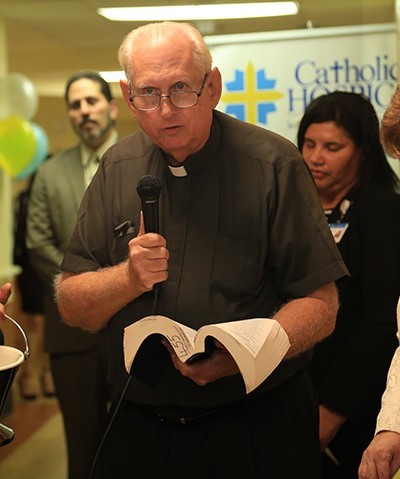 Father David Smith, a chaplain with Catholic Hospice, leads the blessing at the dedication and ribbon-cutting for the new inpatient unit at St. Anne's Nursing Center and Residence.