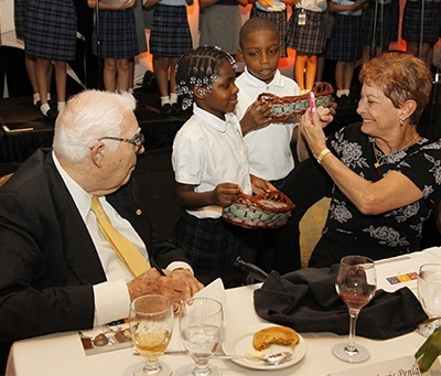 Helen and Norris Penland of St. Vincent Parish in Margate speak to some of the St. Helen second graders who visited each table to pick up guests' pledge cards to the ABCD.