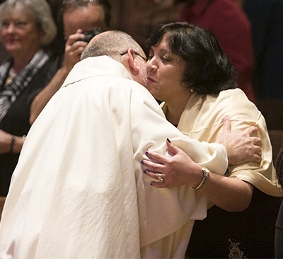 Father Pedro Toledo kisses his wife, Betsy, during the Sign of Peace.