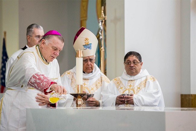 Archbishop Thomas Wenski pours Chrism on the altar of St. Katharine Drexel's new church. Behind him are Archbishop Roberto Lückert León of Coro, Venezuela, and the church's pastor, Father Enrique Delgado.