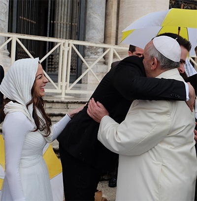 Ryan Ulloa hugs Pope Francis as his new bride, Melissa, looks on.