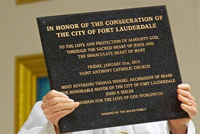 St. Anthony’s pastor, Father Jeremiah Singleton, holds up the plaque commemorating the consecration.