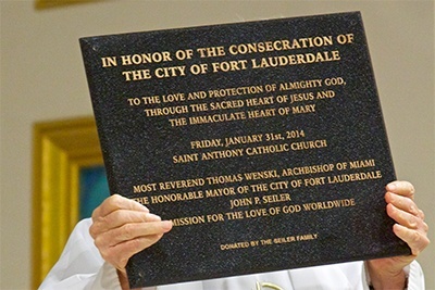 St. Anthony’s pastor, Father Jeremiah Singleton, holds up the plaque commemorating the consecration.