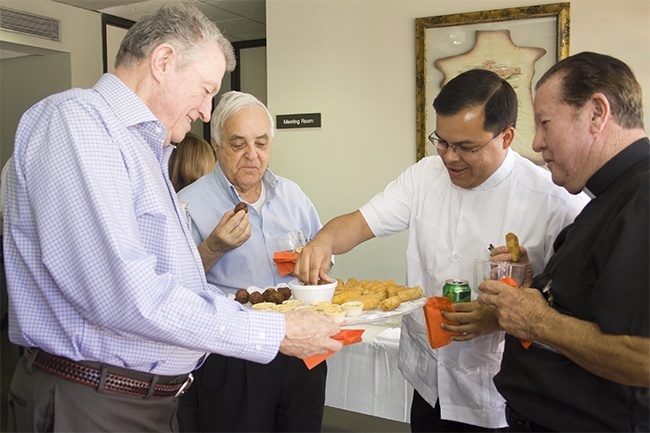 Host Msgr. Jude O'Doherty, pastor of Epiphany Parish, passes out some hors d'oeuvres at the start of the luncheon. With him, from left: Father Hernando Villegas, Father Elvis Gonzalez and Father Jairo Tellez.