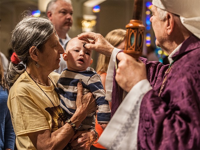 Archbishop Wenski places ashes on the forehead of Sean Tamburrino, 7 months old, as his grandmother, Maria Tamburrino, holds him.