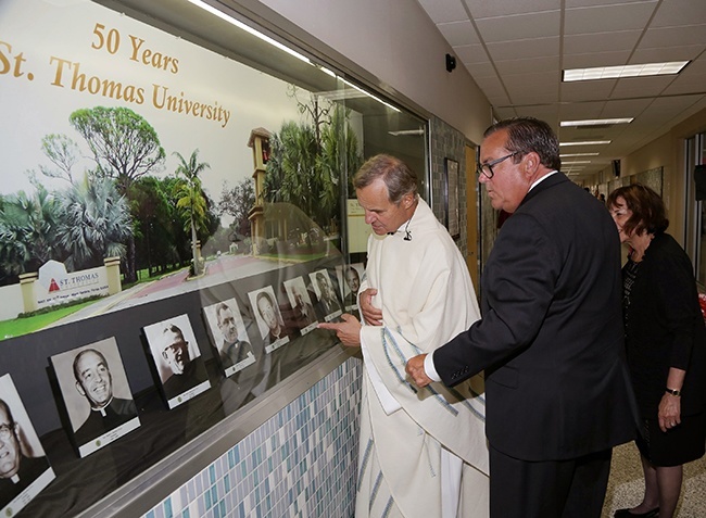 Msgr. Frankly Casale and John Dooner look over a display of the history of St. Thomas University.