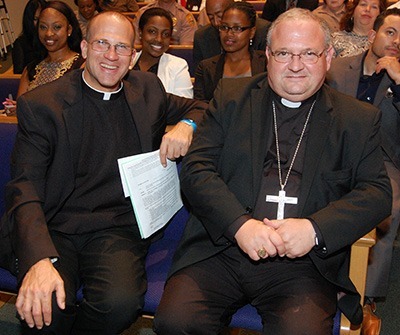 Father Christopher Marino, left, and Auxiliary Bishop Peter Baldacchino listen to the proceedings at PACT's Nehemiah Action Assembly.