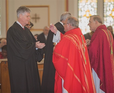 Auxiliary Bishop Peter Baldacchino gives Communion to Appeals Judge Thomas Logue.