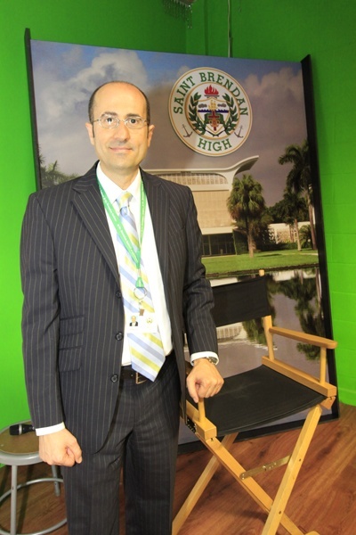 Jose Rodelgo-Bueno poses in front of the green screen of St. Brendan High School's TV studio and media lab.