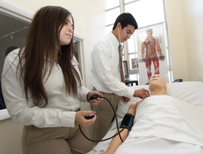 St. Brendan students Andres Rivera, right, who graduated this year, and Ashley Silvarrey, an incoming junior, measure the blood pressure of Hal the medical mannequin.