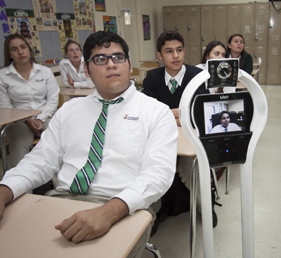 In a demonstration, incoming junior Kristopher Gonzalez (visible on the TV screen) participates in a St. Brendan High class via the school's rolling robot. It allows students to "go" to class while they are sick at home or in the hospital.