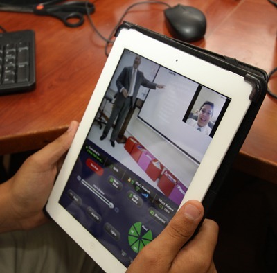 In a demonstration, incoming junior Kristopher Gonzalez (visible on the TV screen) participates in a St. Brendan High class via the school's rolling robot, which he is manipulating in another room. The robot allows students to "go" to class while they are sick at home or in the hospital.