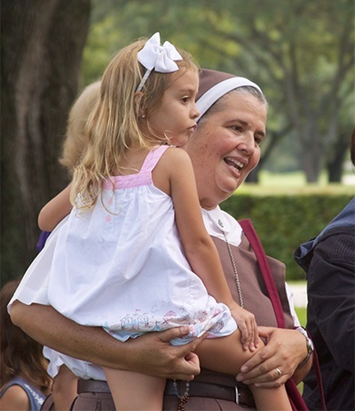 La Hermana Delia Morales, de Las Siervas de los Corazones Traspasados, lleva en brazos a la estudiante de la escuela Blessed Trinity, Carolina Coello, durante la procesión eucarística, dando a la niña de 5 años, un breve descanso de la milla y media de caminata.