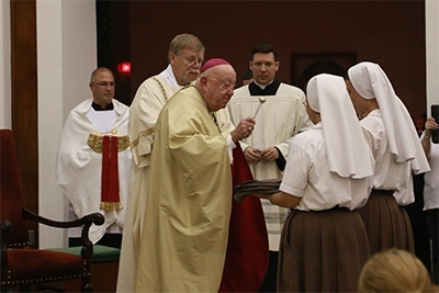 Miami Archbishop Emeritus John C. Favalora blesses the habits of three aspirants of the Servants of the Pierced Hearts who would later profess their vows during the Mass that opened the all-night vigil on the feast of the sacred hearts of Jesus and Mary.