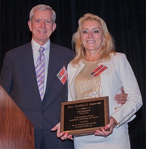 Albert Massey, incoming president of the St. Thomas More Society of South Florida, presents a plaque to outgoing president Cynthia Imperato.