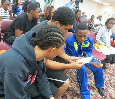 MetroTown participants Josh Moss, David Henderson and Christopher Sanders look at a passport during one of the camp's diversity-awareness activities.