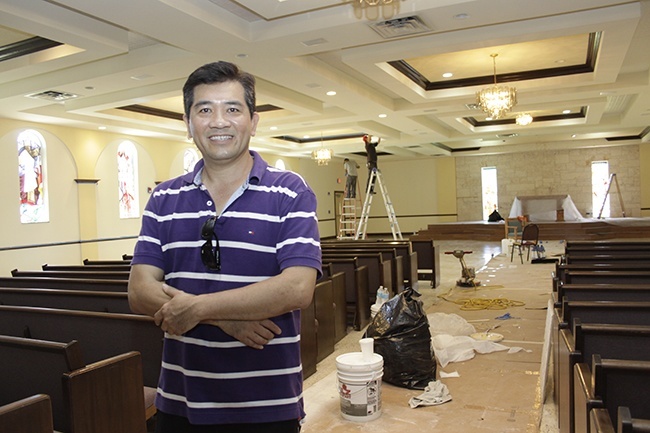 Father Joseph Long Nguyen stands in the middle of the old St. Charles Borromeo Church as volunteer workers from the Vietnamese community prepare it for its reopening as Our Lady of La Vang Vietnamese Mission.