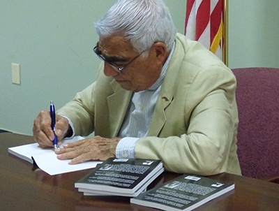 El P. Jorge Chabebe firma copias de su libro durante la presentacion en la Ermita de la Caridad.