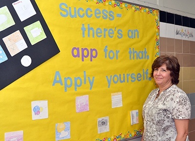 St. Helen School principal Annette Buscemi pauses by a poster in the school's hallway.