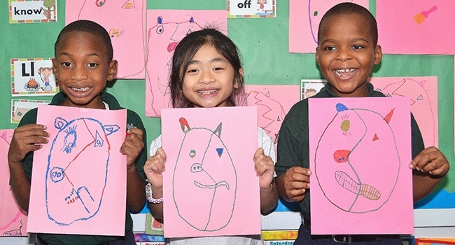 First-graders at St. Helen School show their "Pigcasso" pictures. From left are Gordon Severe, Julie Nguyen and Bichard Deliscar.