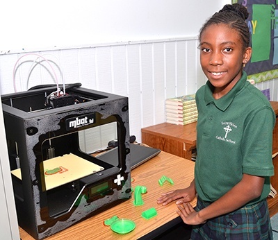 Sixth-grader Kensia Saint-Hilaire shows the school's 3D printer.