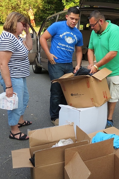 Miami seminarians Andres Pareja (right) and Nick Toledo select donated items to take on one of their daily visits with migrants. Local parishioner Mary Branisteanu, who coordinated collection, is at left.