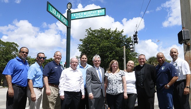 Posing with Father James Murphy's siblings after the unveiling of the new street sign, from left: Miami Lakes councilmen Frank Mingo, Tony Lama and Tim Daubert, Dennis Murphy, councilman Nelson Rodriguez, Mayor Wayne Slaton, Madeleine Keating, Jacqueline Austen, Our Lady of the Lakes' current pastor, Father Jose Alvarez, and councilmen Ceasar Mestre and Manny Cid.