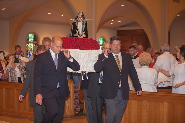 Carlos Silva, Roger Machin and other men carry a statue of Our Lady Guardian of the Faith into Mass.