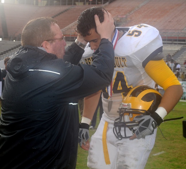 Jesuit Father Guillermo Garcia-Tunon, principal of Belen Jesuit Prep School in Miami, blesses senior defensive lineman Ricardo Cuevas after giving Cuevas his silver medal at the FHSAA Class 3A Football Finals at the Citrus Bowl in Orlando, Dec. 18. The Belen Jesuit Wolverines lost to Pensacola 28-7 in Belen's first appearance in the state final. The farthest Belen had previously advanced was the second round of the playoffs.